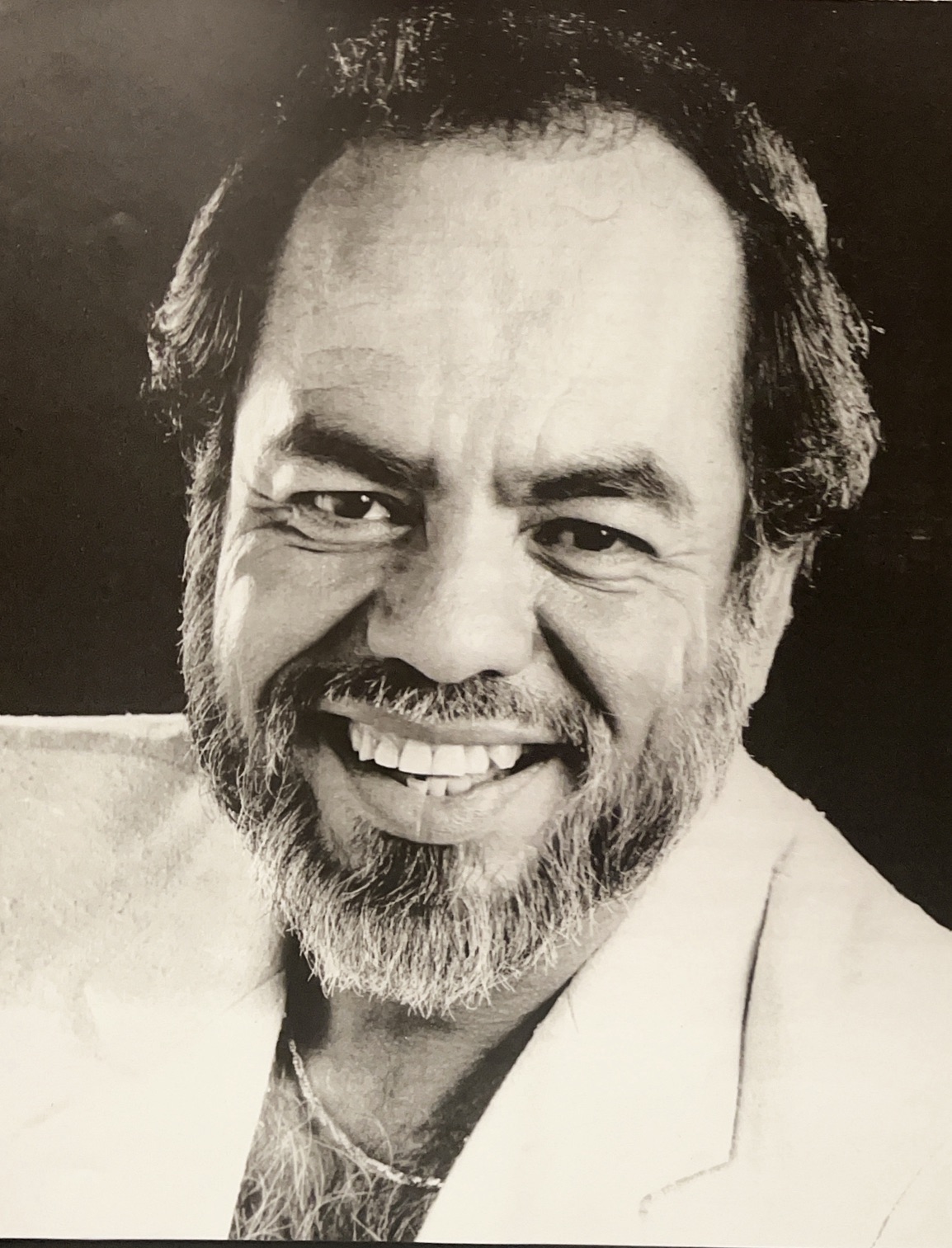 Little Joe Hernandez, smiling broadly while wearing a light-colored jacket.