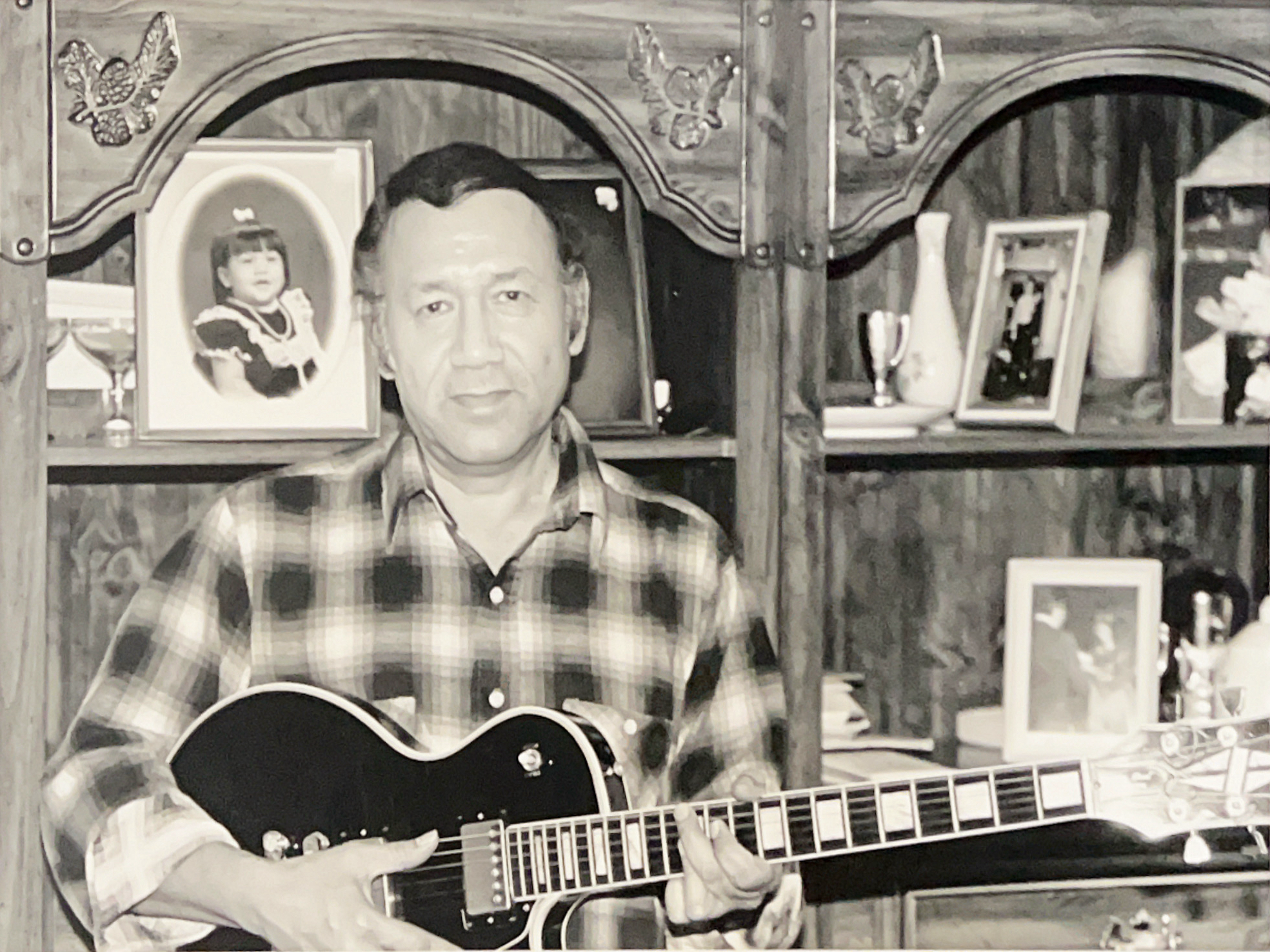 Manuel Donley wearing a plaid shirt and holding an electric guitar.